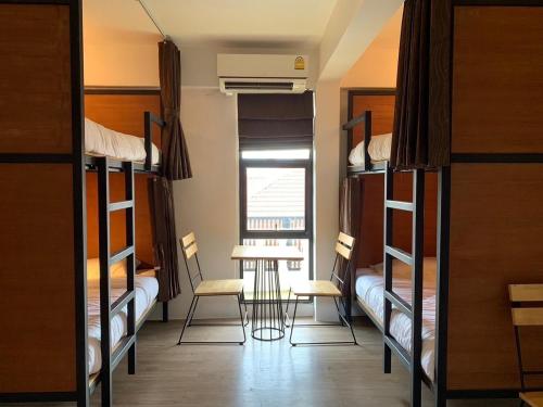 a room with bunk beds and a table and chairs at Lazy Gibbon 2 Chiang Mai - Haiya in Chiang Mai