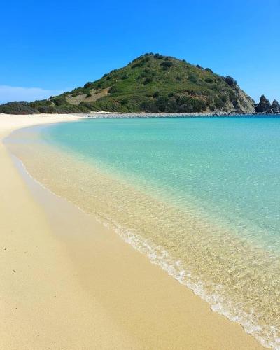 an empty beach with a hill in the background at Su Furriadroxiu in San Vito