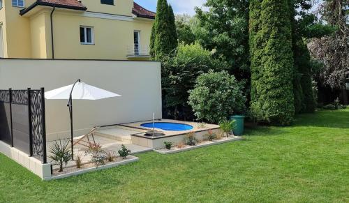 a backyard with a swimming pool and an umbrella at Villa Kreuzbergl - Doppelzimmer in Klagenfurt