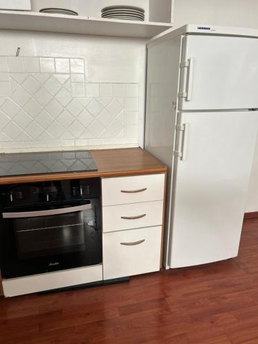 La cuisine est équipée d'appareils électroménagers blancs et d'un réfrigérateur. dans l'établissement Duplex cosy, à Draguignan