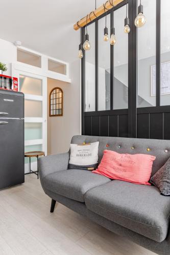 - un canapé gris avec deux oreillers dans le salon dans l'établissement Escale à Clisson - L'atelier, à Clisson