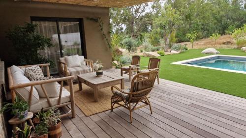 - une terrasse en bois avec des chaises et une table à côté de la piscine dans l'établissement VILLA AVEC PISCINE PORTO-VECCHIO CORSICA, à Porto-Vecchio