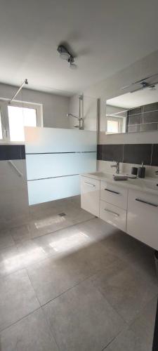 une grande cuisine avec des placards blancs et un évier dans l'établissement Logement cosy, piscine, terrain de pétanque, vélos, entre centre ville et lac, à Parentis-en-Born