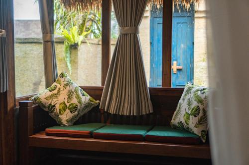 a bench in front of a window with two pillows at Lawani Resort in Tegalalang