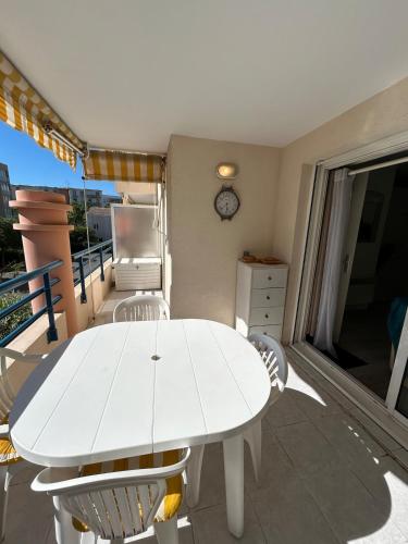 une table blanche et des chaises sur un balcon dans l'établissement Appartement fréjus avec piscine - plage - parking, à Fréjus