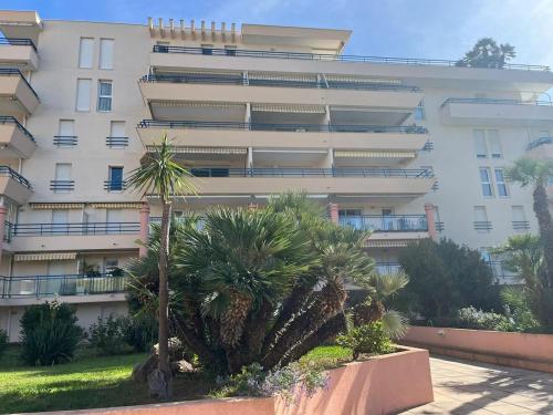 un grand bâtiment blanc avec des palmiers devant dans l'établissement Appartement fréjus avec piscine - plage - parking, à Fréjus