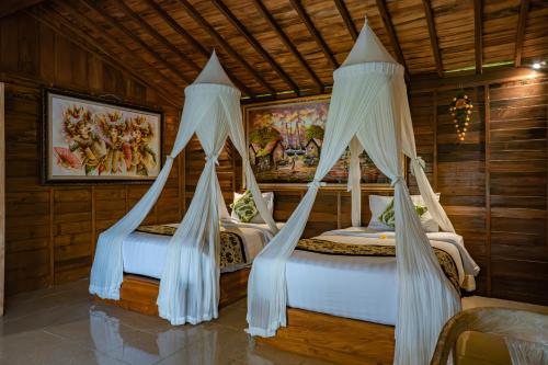 two beds in a room with drapes at Lawani Resort in Tegalalang