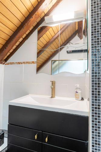 une salle de bain avec un lavabo et un miroir dans l'établissement Cocon Normand - 100m de la plage, à Étretat