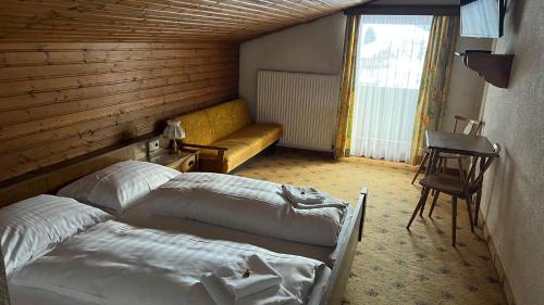 a bedroom with two beds and a yellow couch at Haus Alpina by Châtel Reizen in Grossarl