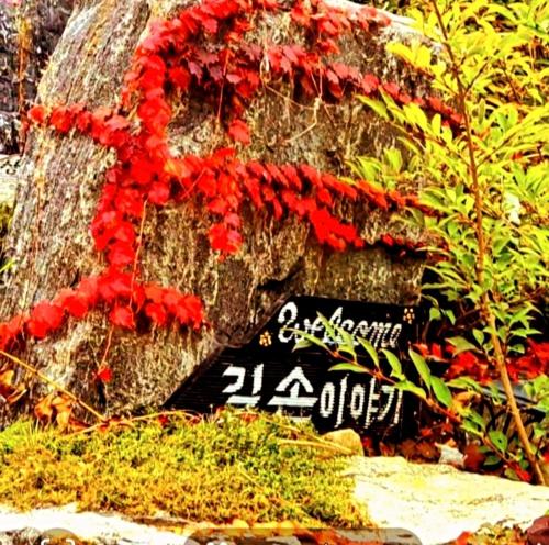 a sign with red flowers on top of a rock at Gilson Story Pension in Pyeongchang 