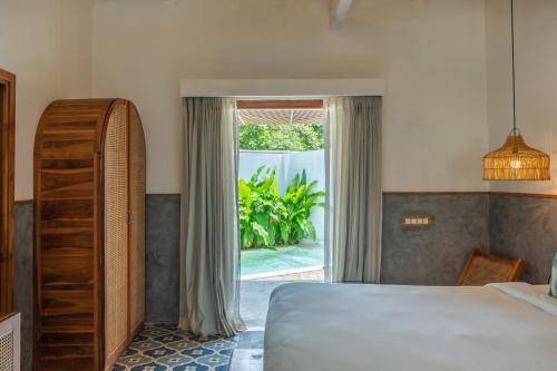 a bedroom with a bed and a large window at Azora by Ayatana, Goa in Morjim