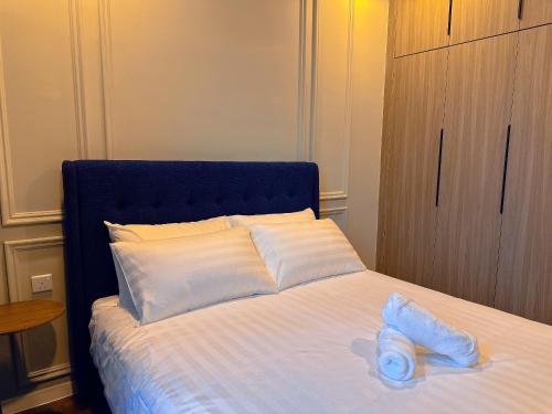 a bed with a blue headboard and white pillows at Bloomsvale Residence in Kuala Lumpur