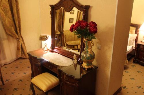 a vase of flowers on a vanity with a mirror at Hotel Lux Angliter in Vologda