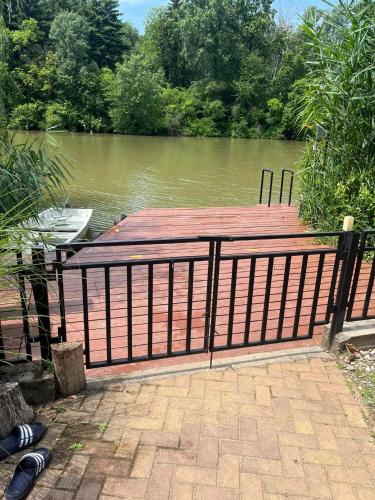 a wooden dock with a fence next to a body of water at Csuka48 Apartman in Szarvas