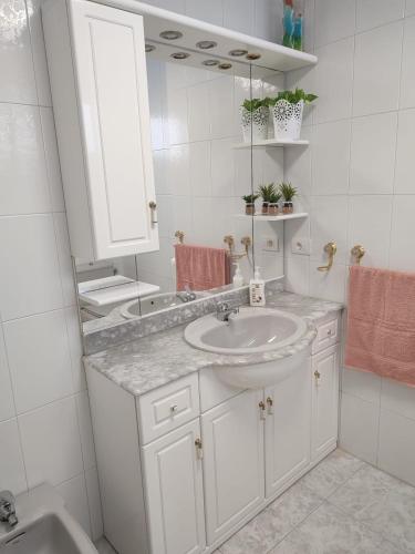 a white bathroom with a sink and a mirror at Apartamento vacacional Meira in Meira