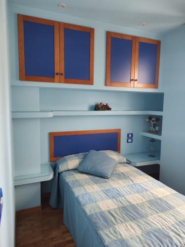 a bedroom with a bed with blue walls and wooden cabinets at Apartamento vacacional Meira in Meira