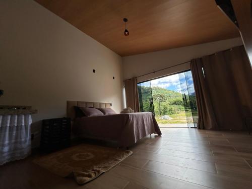 a bedroom with a bed and a large sliding glass door at Sítio da vó Noeme in Alto Caparao