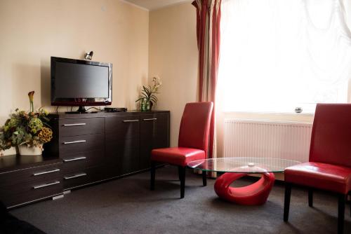a living room with a table and two chairs and a tv at Hotel Wiktoria in Wiązowna
