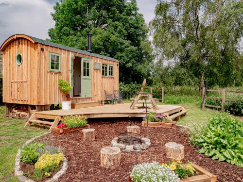 a wooden cabin in a garden with a patio at Luxury Shepherds Hut in Stonehouse