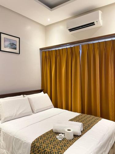 1 dormitorio con 1 cama con cortina amarilla en White Sand Bar Inn, en Manjuyod