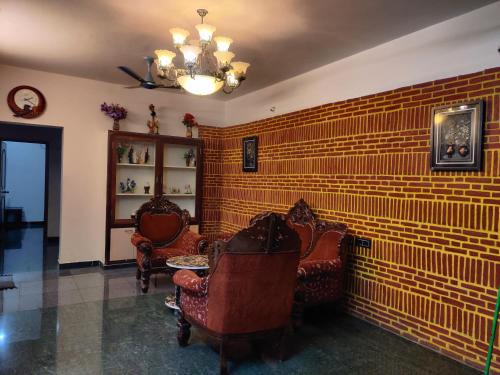 a living room with chairs and a brick wall at Holiday home stay Puducherry in Puducherry