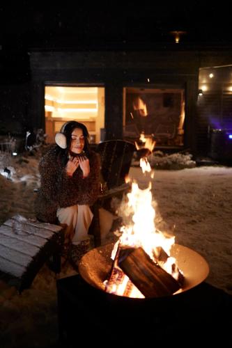 a woman talking on a cell phone next to a fire at Villa La Roca Garden and Spa in Kościelisko