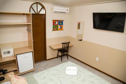 a room with a small desk and a tv on the wall at Pousada da Terra in Natal