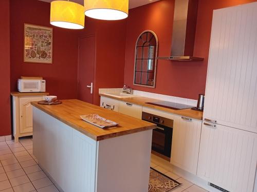 - une cuisine avec des murs rouges et un comptoir blanc dans l'établissement Un vrai paradis avec terrasse face à la mer, à Plougasnou