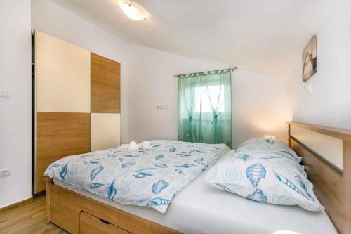 ein Schlafzimmer mit einem Bett mit blau-weißer Bettwäsche in der Unterkunft Apartment in Malinska - Insel Krk 38057 in Malinska