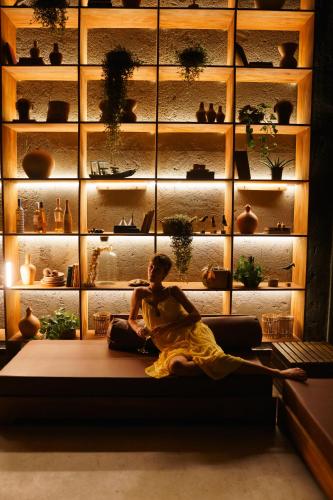 a woman sitting on a couch in front of a wall of plants at SITIO VILLA DA MATA in São Miguel dos Milagres
