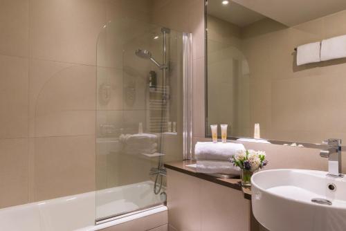 a bathroom with a shower and a sink and a tub at Hotel de Neuve by Happyculture in Paris