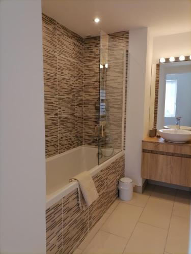 une salle de bain avec une baignoire et un lavabo dans l'établissement Maison de village Les Marronniers, à Anse