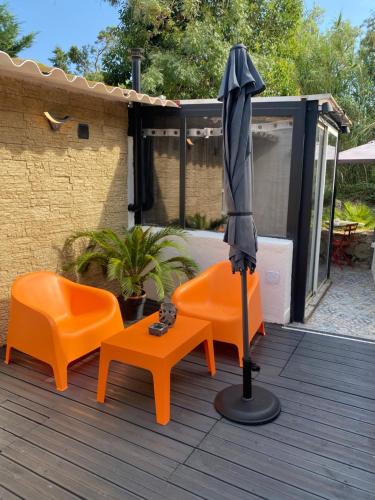 a patio with two orange chairs and an umbrella at suite phantastica in Les-Pennes-Mirabeau