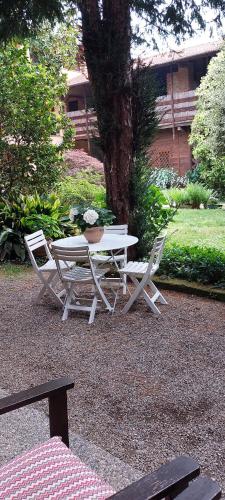 a picnic table and two chairs around a tree at B&B il Cortile Malpensa in Casorate Sempione