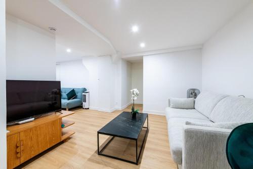 un salon avec un canapé et une télévision dans l'établissement Avenue Breteuil Family - 11 pers - Unique - Cosy, à Paris