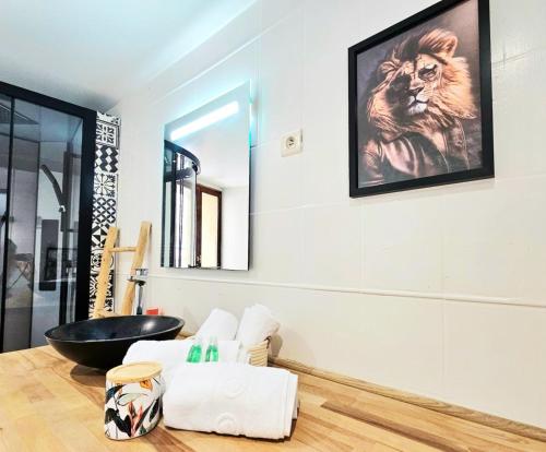 La salle de bains est pourvue d'une baignoire noire et d'une peinture au lion sur le mur. dans l'établissement Jungle, Maison au Coeur des remparts - L'Avenue des Voyageurs, à Boulogne-sur-Mer
