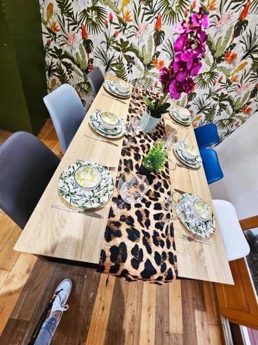 une table en bois avec des assiettes et des fleurs dessus dans l'établissement Jungle, Maison au Coeur des remparts - L'Avenue des Voyageurs, à Boulogne-sur-Mer