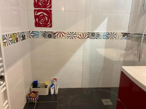 La salle de bains est pourvue d'un mur en carrelage blanc et d'une étagère. dans l'établissement Nid de verdure proche océan, à Anglet