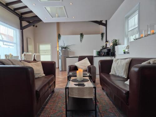 a living room with brown couches and a table at Gemütliches Loft mit Terrasse im ehemaligen Bahnhof Kalenborn in Vettelschoß