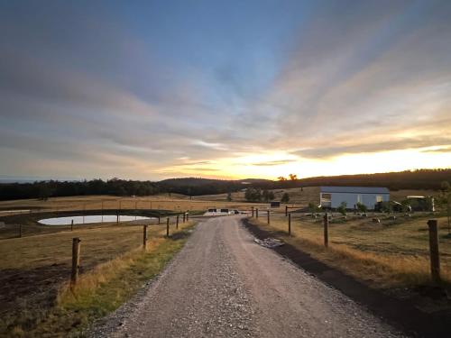 a dirt road in a field with two ponds at Banjos Cabin Gippsland - Luxury Eco Stay - King Bed, Pond Valley Views, Fireplace in Seaton