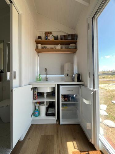 a kitchen in a tiny house with a sink at Banjos Cabin Gippsland - Luxury Eco Stay - King Bed, Pond Valley Views, Fireplace in Seaton