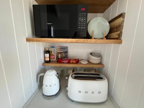 a kitchen with a toaster and a microwave on a shelf at Banjos Cabin Gippsland - Luxury Eco Stay - King Bed, Pond Valley Views, Fireplace in Seaton