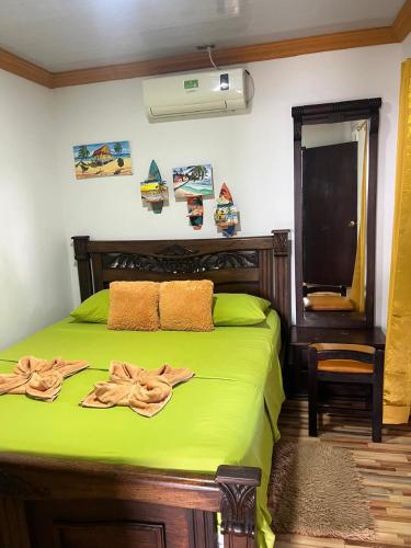 a bedroom with a green bed with towels on it at Posada Ashanty in Providencia