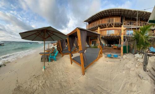 a building on the beach with a table and an umbrella at Cabañas W Beach in Cartagena de Indias