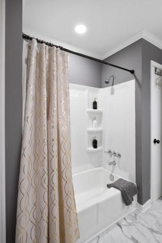 a bathroom with a tub and a shower curtain at Charming Retreat with Pool Table in Chesterfield! in Chesterfield