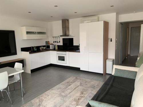 une cuisine avec des armoires blanches, une table et un canapé dans l'établissement Petit Saint James Croisette, à Cannes