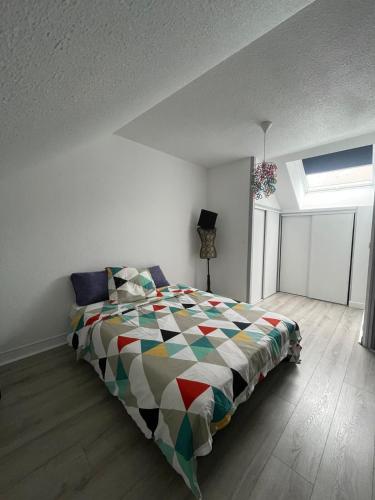 une chambre avec un lit avec une couette colorée dans l'établissement Duplex cosy, à Vesoul