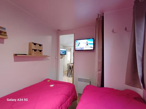 - une chambre avec 2 lits et une télévision murale dans l'établissement Mobilhome camping Ernest Renan Louannec, à Louannec
