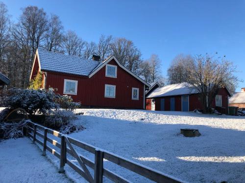 a red house with a fence in the snow at Stuga nära Ullared Mitt i Åkulla bokskogar in Rolfstorp
