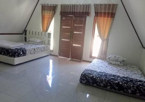 a bedroom with two beds and a window at Penginapan & Homestay Ratu Pantai Geopark Ciletuh in Cikadal